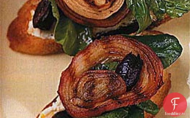 Pâine la grătar acoperită cu rucola, brânză de capră, măsline și ceapă